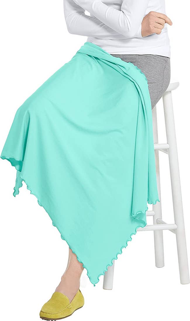 model sitting on a stool, knees and lap covered by the blanket