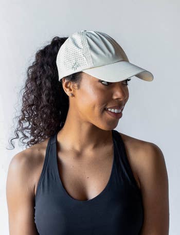 Model in a grey baseball cap with a high ponytail coming out of the back  
