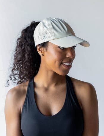 Model in a grey baseball cap with a high ponytail coming out of the back  