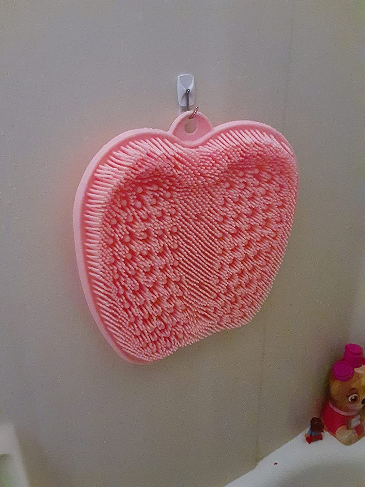 reviewer image of pink foot scrubber hanging from hook in shower