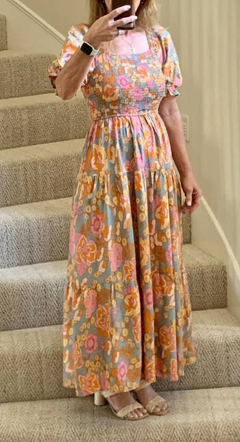 Person in floral dress stands on stairs, suitable for a shopping article on spring fashion trends