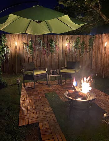 a backyard with teak tiles laid down around a fire pit