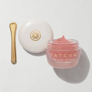 Tatcha Kissu lip mask in a jar with an applicator on a white surface
