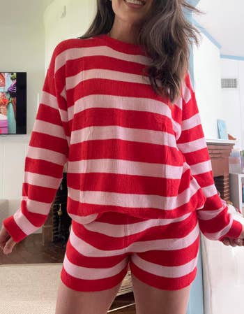 Person wearing cozy reddish  and achromatic  striped sweater and shorts acceptable   indoors, smiling