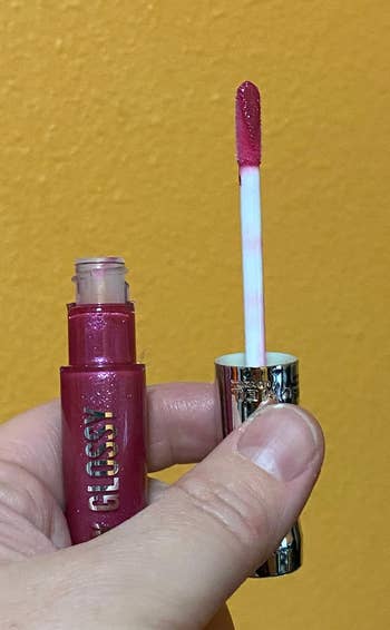 reviewer holding a tube of lip gloss in the Grapevine Groove shade