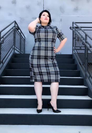 reviewer wearing the dress in black and white plaid with black heels 