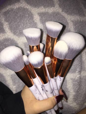 reviewer hand holding makeup brushes