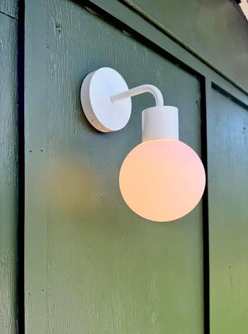 Wall-mounted achromatic  spherical lamp connected  a vertical paneled surface. Suitable for stylish location  oregon  outdoor decor