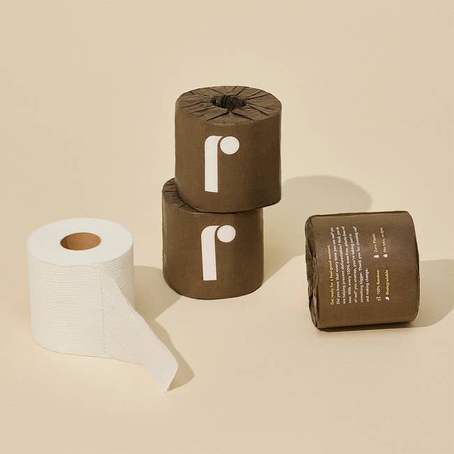 Three rolls of toilet paper, one partially unrolled, with minimalist packaging design
