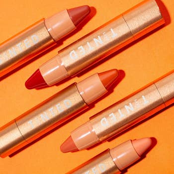 several tubes of the huestick corrector in various shades of orange/red/pink