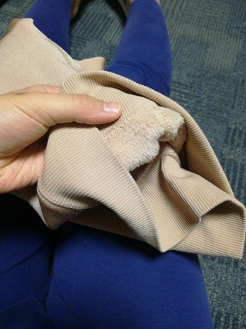 reviewer showing the fleece lining on beige leggings