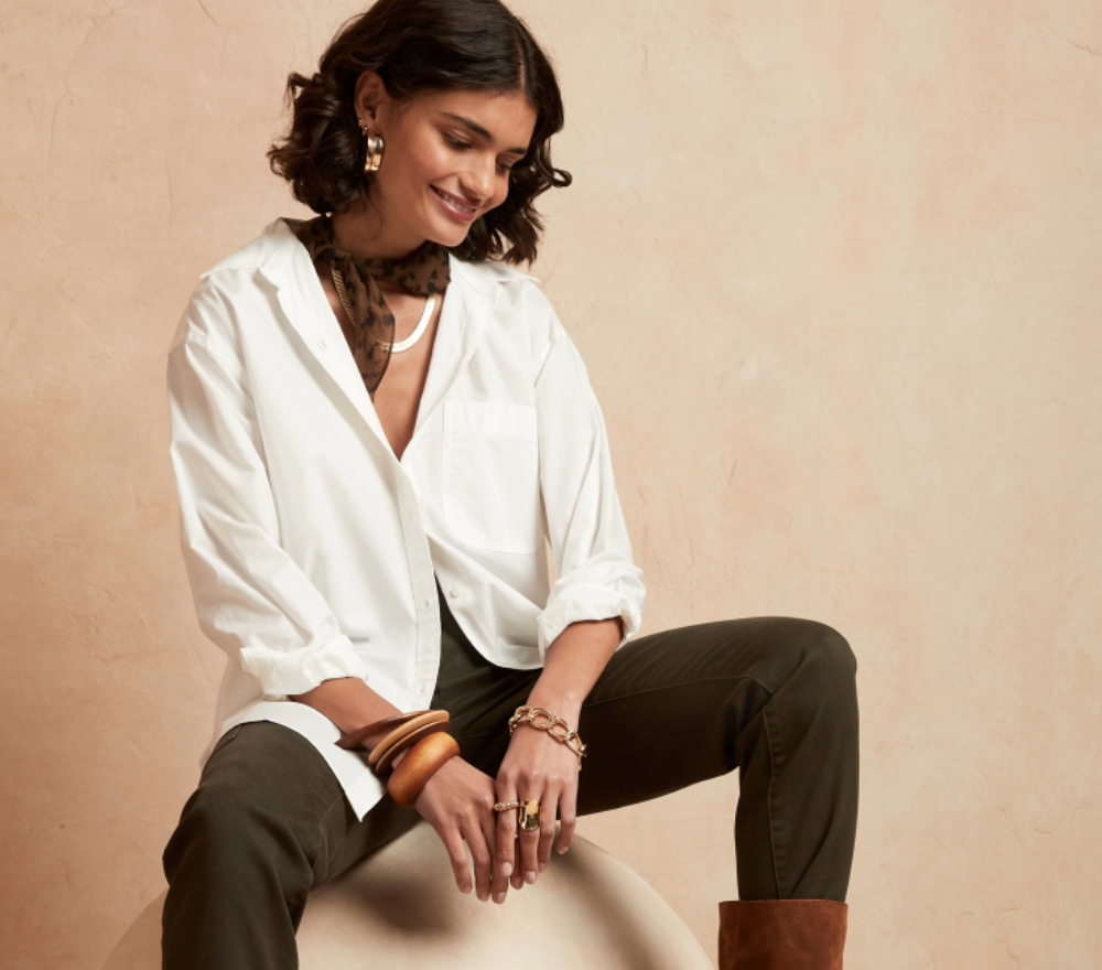 Model is wearing a white loose button-down top and black pants