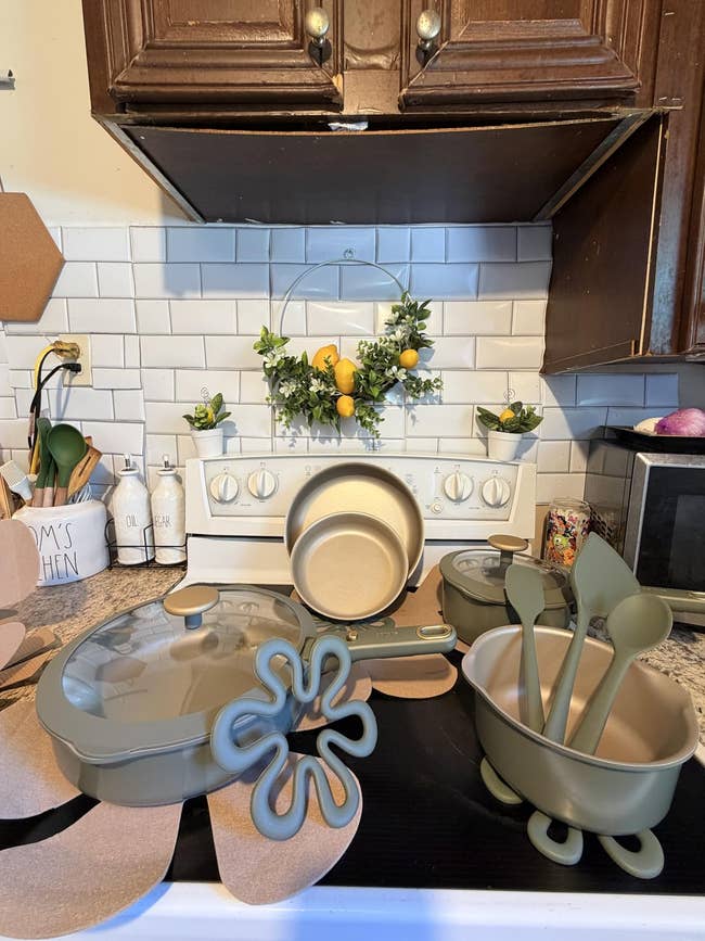 Kitchenware acceptable   connected  a stove includes pots, pans, and utensils. Lemon decor hangs supra  stove against achromatic  tile backsplash