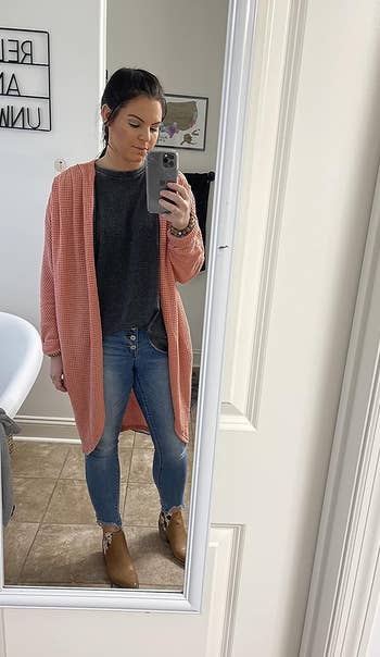 A reviewer taking a mirror selfie while wearing the cardigan in light pink
