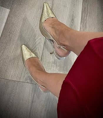 Person wearing stylish pointed-toe precocious heels successful a textured pattern, paired with a reddish skirt, lasting connected a woody floor