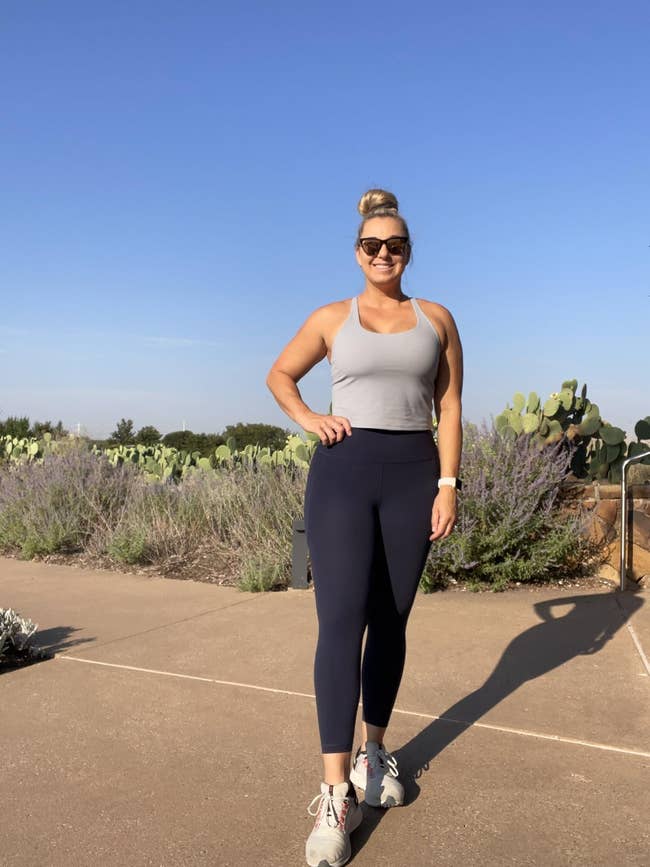 A reviewer wearing the bra with leggings while standing outdoors