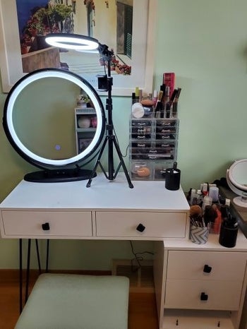 reviewer photo of makeup table setup with large circular lit vanity mirror