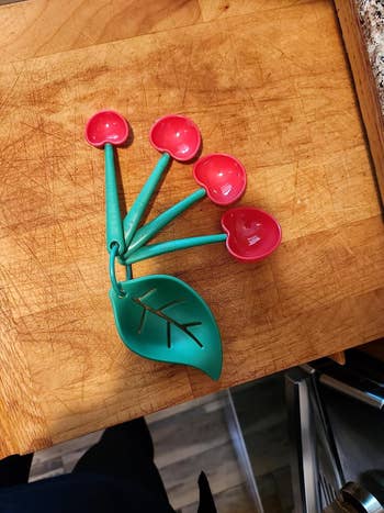 Measuring spoons shaped like cherries on a wooden surface, ideal for kitchen use