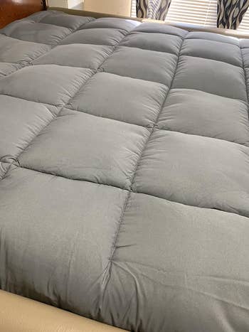 A reviewer photo of the grey mattress topper