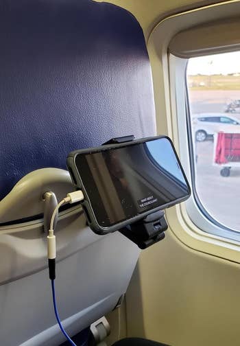 same reviewer's smartphone mounted on an airplane seat back, connected to headphones