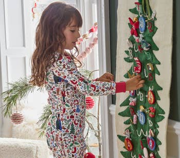 a child playing with a long rifle paper tapestry advent calendar with felt pieces