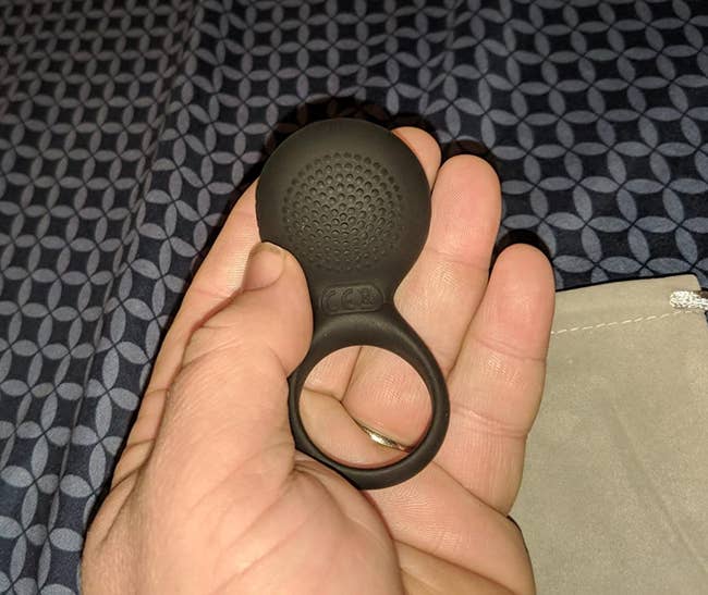 Reviewer holding black cock ring to display textured pad