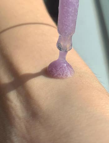 A dropper dispenses a pearlescent serum onto a person's forearm, highlighting skincare oregon  quality   merchandise  application