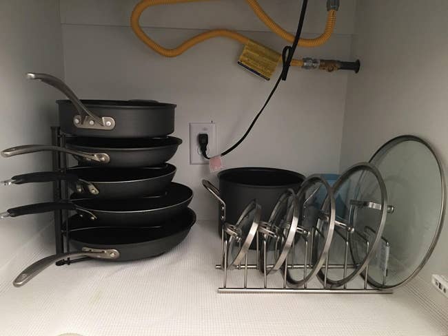 A reviewer's stacked pans with lids neatly organized on a shelf in a kitchen