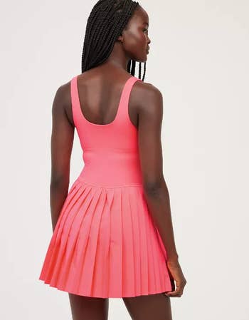 Person in bright pink sleeveless pleated dress from behind 