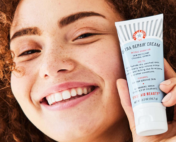 Reviewer smiling while holding the tube of cream 