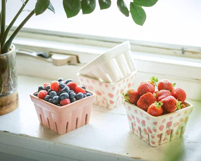 Assorted fresh berries in decorative baskets on a windowsill