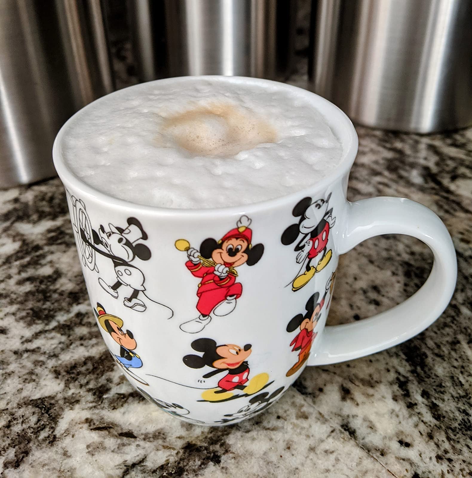 a white ceramic mug with different versions of mickey mouse on it