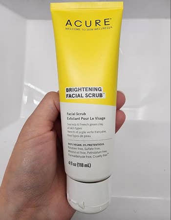 Hand holding ACURE Brightening Facial Scrub 