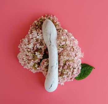 Faux marble porcelain dildo on bed of pink flowers