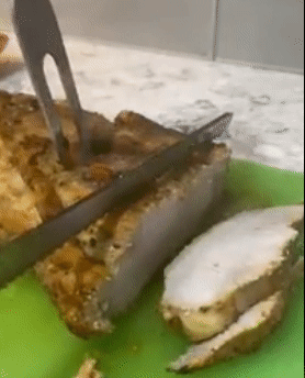 Reviewer using long knife to cut through a thick slab of ham 