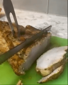 Reviewer using long knife to cut through a thick slab of ham 