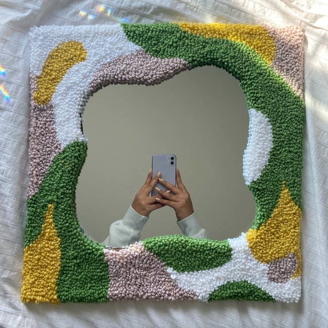 a rug mirror with pink, yellow, green, and white colors throughout