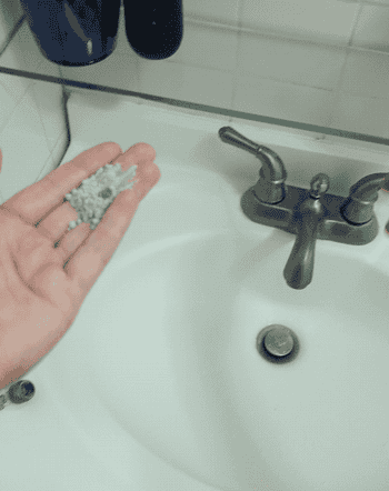 a gif of a reviewer applying water to a small bit of powder in their hand and mixing it while it turns into a green paste 