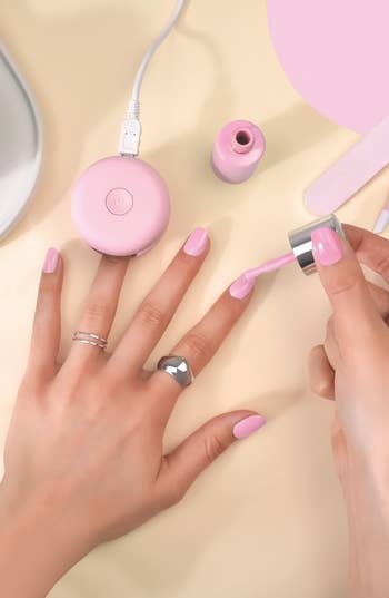 model painting nails pink, curing one nail with LED lamp