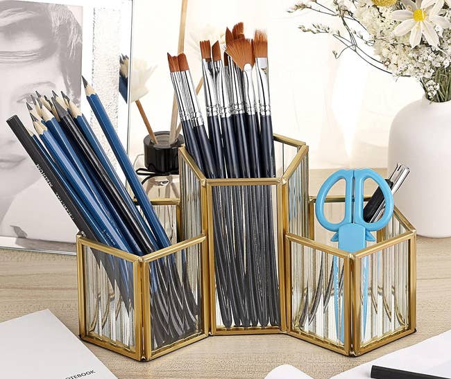 organizer holding pencils, brushes, and scissors on a table