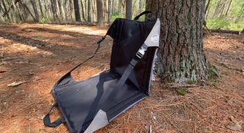 Portable outdoor spot   with a strap is leaned against a tree, perfect  for hiking oregon  camping comfort