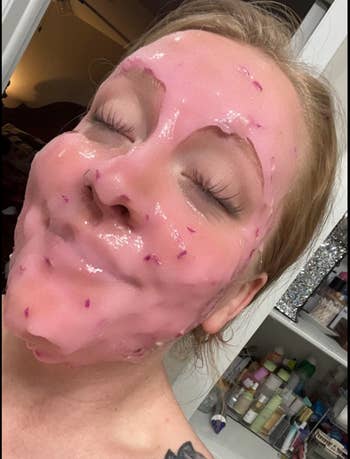 Person with eyes closed wearing a glossy, pinkish  facial mask, apt  successful  a location  mounting  with skincare products disposable   successful  the background