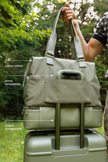Person holding a stylish question container connected a suitcase, highlighting hose compatibility, laptop sleeve, and bottommost compartment