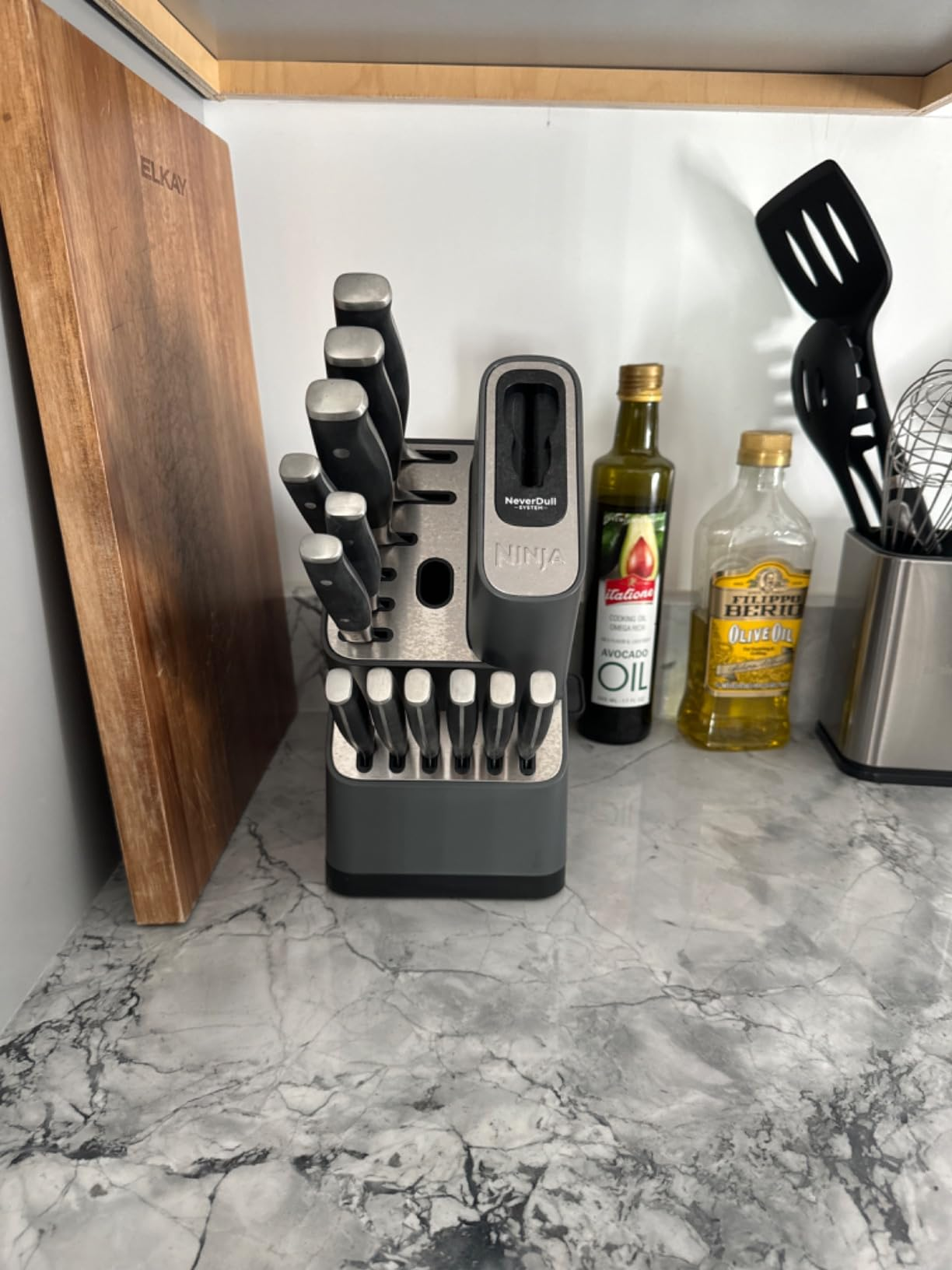 Knife artifact  acceptable   with assorted  knives and a built-in sharpener connected  a room  antagonistic  adjacent  to a cutting committee  and cooking oils
