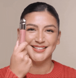 gif of a model putting two dots of blush on each cheek and blending with a brush and their finger