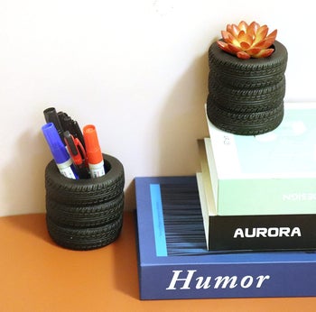 two tire cups. one with pens and one with a small succulent. 