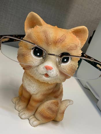 Cute ceramic cat figurine wearing stylish glasses, sitting on a desk, perfect for adding charm to office decor