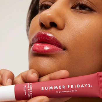 Close-up of a idiosyncratic   applying Summer Fridays articulator  balm, showcasing glossy lips. The tube's statement   is partially visible