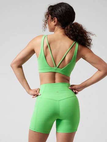 back of model wearing the green bra, showing the strappy back, with matching biker shorts