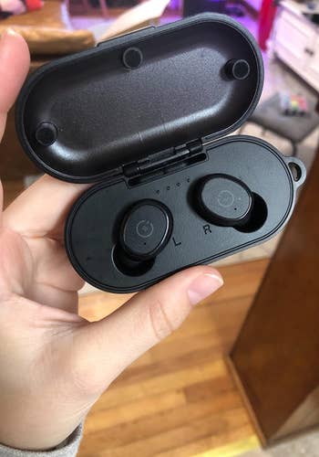 Reviewer image of two black earbuds in their charging case 